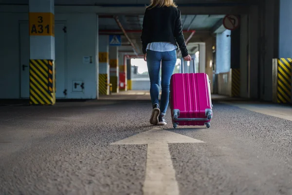 Foto de la parte posterior de la rubia con equipaje rosa caminando a lo largo del pasaje en el aeropuerto . — Foto de Stock