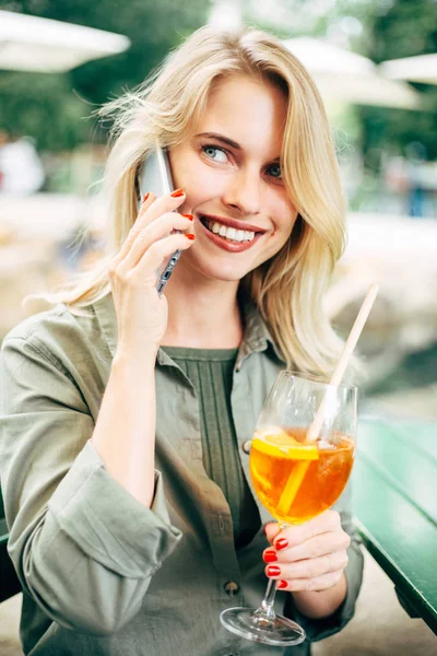 Obraz szczęśliwej Blondynki z koktajlem w dłoniach rozmawiając na telefon na ulicy. — Zdjęcie stockowe