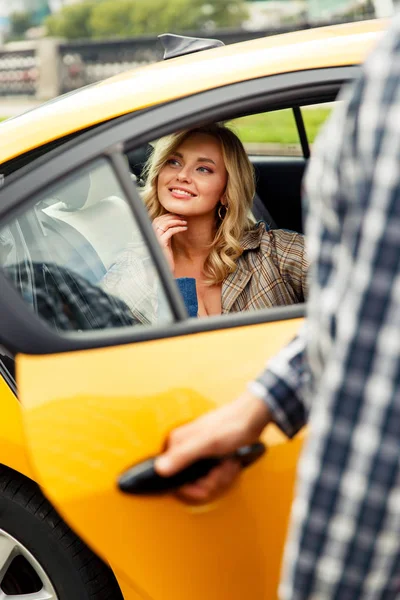 Photo of man opening taxi door where happy blonde sits on summer. — Stock Photo, Image