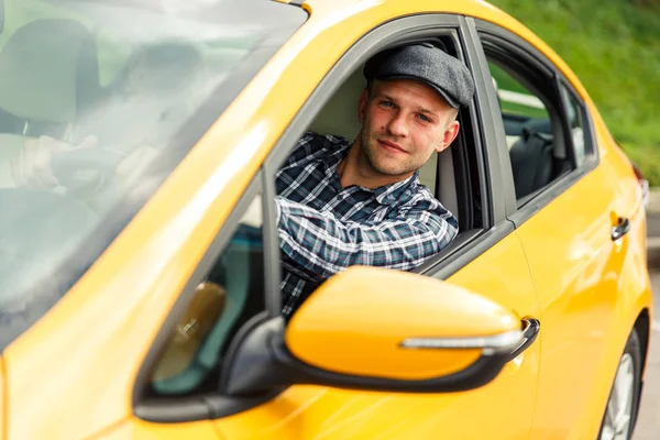여름에 노란색 택시에 앉아 격자 무늬 셔츠에 드라이버의 사진. — 스톡 사진