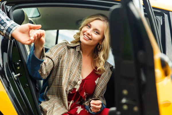 Foto de homem dando a mão a mulher loira feliz sentada no banco de trás do táxi . — Fotografia de Stock