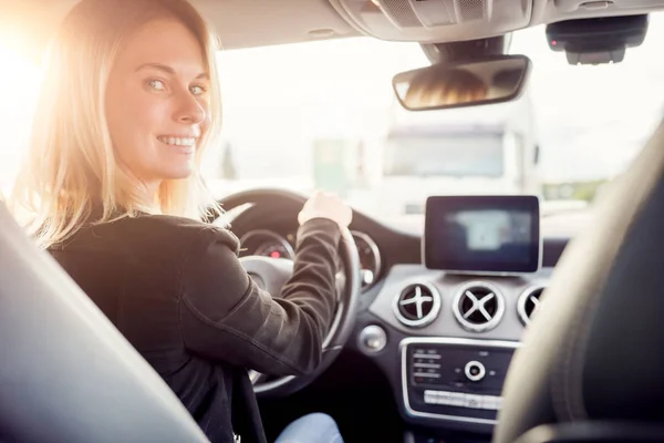 Bild av ung blondin tittar på kameran medan du sitter vid ratten i bilen. — Stockfoto