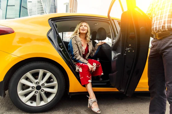 Photo of young blonde in long dress sitting in back seat of taxi in afternoon — Stock Photo, Image