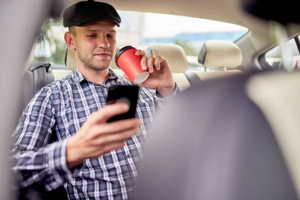 Foto de un pasajero con teléfono en la mano sentado en el asiento trasero del coche —  Fotos de Stock