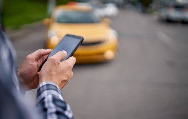Bulanık arka plan taksisinde telefonu elinde tutan adam.