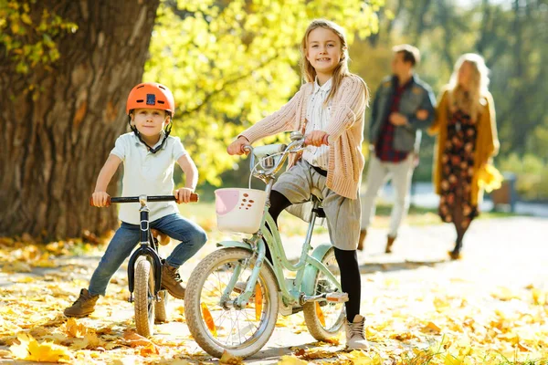 Foto di ragazza e ragazzo in casco in bicicletta nel parco autunnale . — Foto Stock