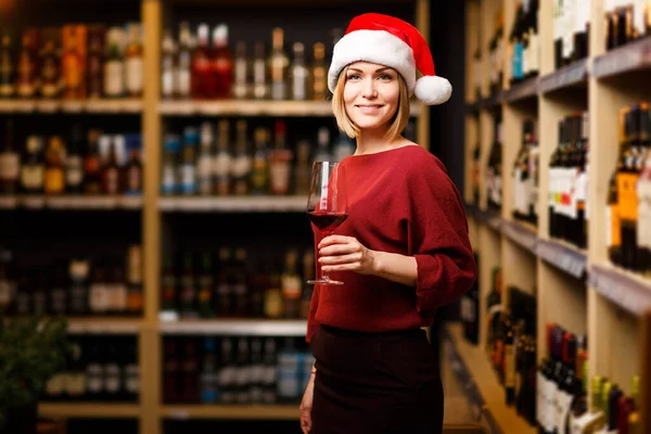 Immagine di ragazza felice in cappello di Babbo Natale con vetro nelle mani del negozio — Foto Stock