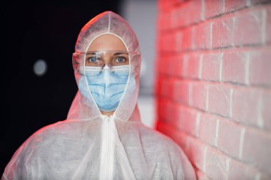 Tuğla duvarın arka planında koruyucu giysili doktor.