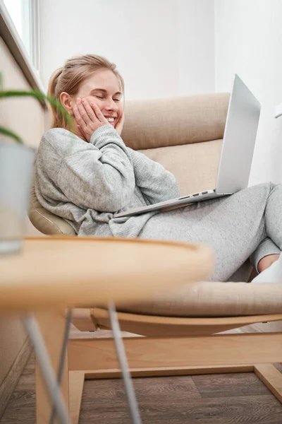 Boldog nő szürke öltönyben, laptoppal a kezében, székben ülve. — Stock Fotó