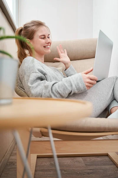 Щаслива блондинка в сірому домашньому костюмі з ноутбуком в руках — стокове фото