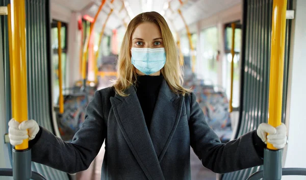 Rubia en máscara médica mirando a la cámara mientras está de pie en el salón de autobuses . — Foto de Stock