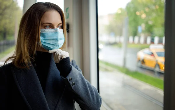 Бажана жінка в медичній масці стоїть біля вікна в автобусі . — стокове фото