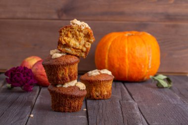 Ahşap arka planda lezzetli taze çörekler. Arka planda bal kabağı ve elma var. Sonbahar teması. Kekler birbirlerinin üstünde duruyorlar.