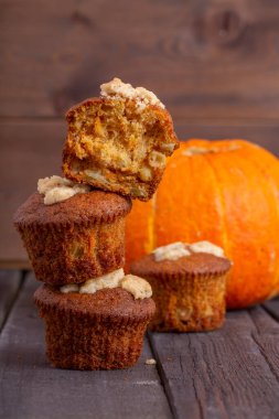 Ahşap arka planda lezzetli taze çörekler. Arka planda bal kabağı ve elma var. Sonbahar teması. Kekler birbirlerinin üstünde duruyorlar.