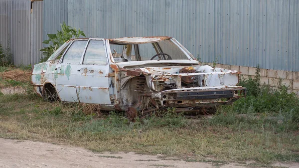 O velho corpo do carro desmontado fica ao lado da cerca — Fotografia de Stock