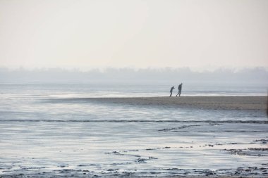 Kumsalda yürüyen çift.