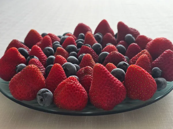 Güneş ışığının altındaki bir masada, bir kasede taze çileklerin yakın çekimi.