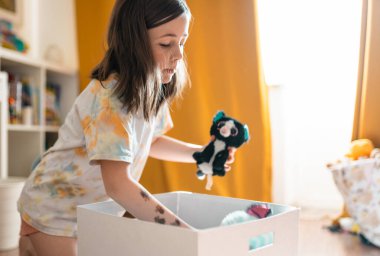Child cleans up her toys. Little girl tydies up her room..