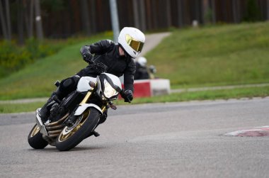 Süper spor motosikletini süren siyahlı yakışıklı motosikletçi.