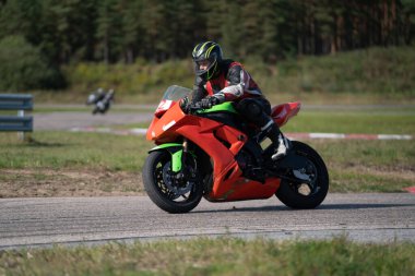 Süper spor motosikletini süren siyahlı yakışıklı motosikletçi.