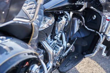 Krom motosiklet. Hisse. Üzerinde krom detaylar ve motosikletçi kıyafetleri olan yeni siyah motosikletin yan görüntüsü. Krom detaylar motosiklet yolculuktan önce bozkır manzarasını yansıtır