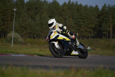 Süper spor motosikletini süren siyahlı yakışıklı motosikletçi.