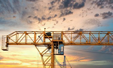 Endüstriyel vinçler ve güneş doğarken siluetler inşa etmek