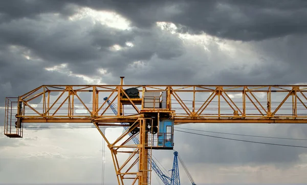 Industrial construction cranes and building silhouettes over sun at sunrise