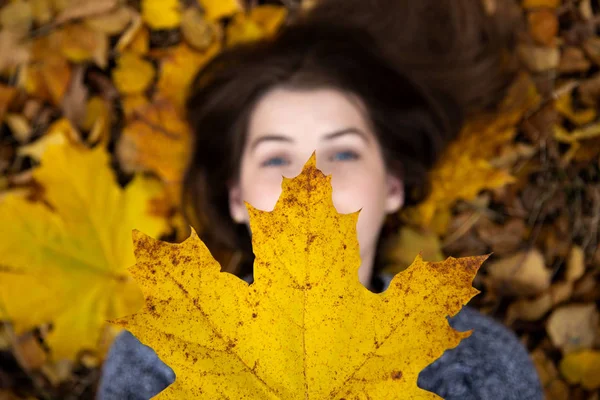 Vista superior de una linda chica con ojos azules, que en el otoño se encuentra o —  Fotos de Stock