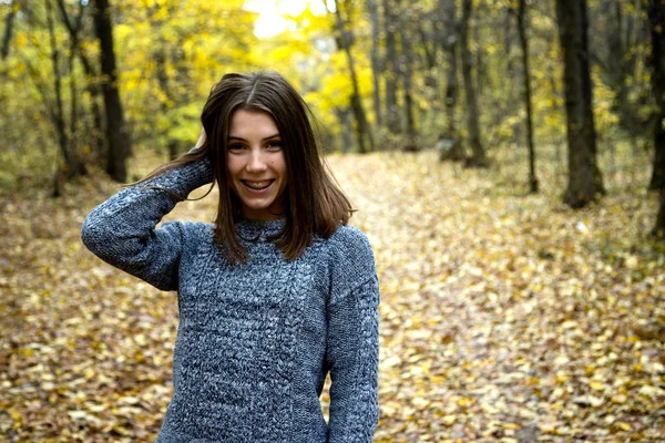 Linda chica en un suéter gris con frenos en los dientes se para en t —  Fotos de Stock