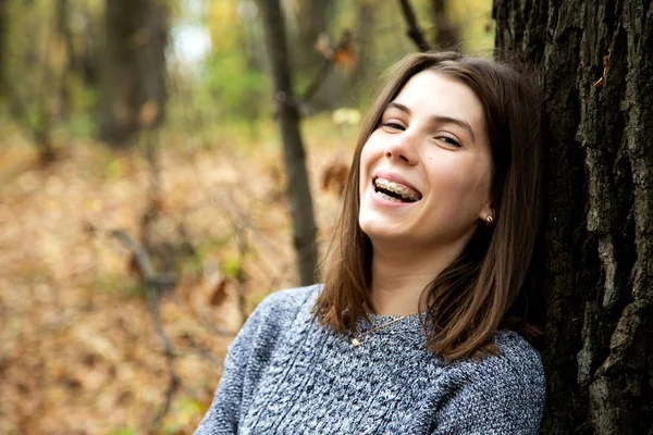 Молодая красивая девушка с брекетами на зубах в сером свитере — стоковое фото