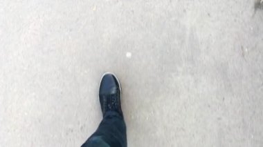 Spor ayakkabı içinde asfalt üzerinde yürüyen adam ayak ilk kişi görünümü.