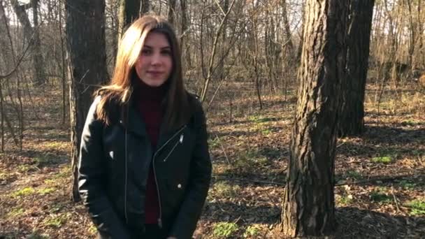 Udendørs portræt af ung smuk kaukasisk teenager pige smilende og kigger ind i kameraet, skovvej på en blæsende dag . – Stock-video