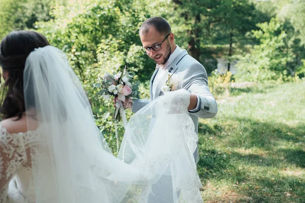 Novio barbudo en una chaqueta gris y gafas sosteniendo un velo o casado —  Fotos de Stock