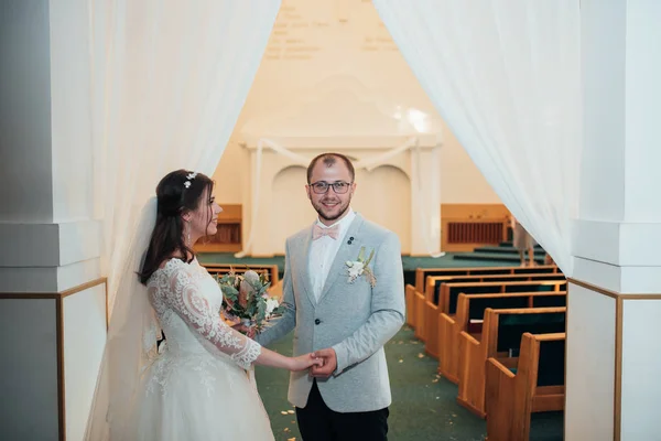 Unga bruden och brudgummen på deras bröllopsdag i en kyrka — Stockfoto