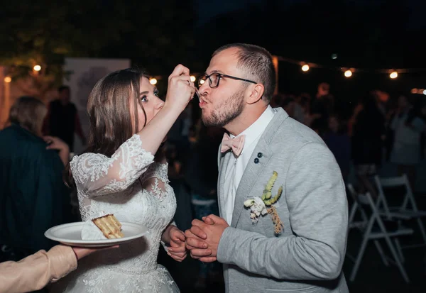 Nevěsta a ženich na večírku vyjmout a zkuste svatební dort — Stock fotografie