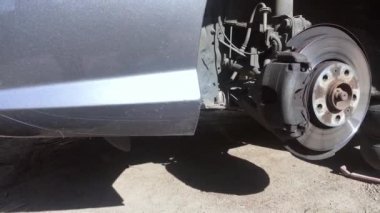 Gri metalik araba yavaş çekimde tekerlek değişimi için jak üzerinde
