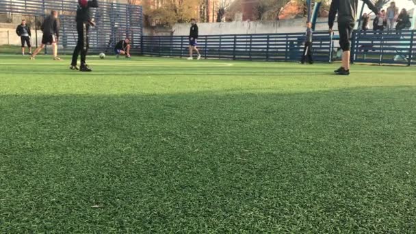 LVIV, UCRAINA - 14 APRILE 2019: Ragazzi la sera in una giornata di sole a giocare a calcio su un mini campo in erba artificiale — Video Stock