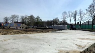 Lviv, Ukrayna - 14 Nisan 2019: Stadyumun inşaatı. Beton yolda traktörle seyahat eden işçiler.