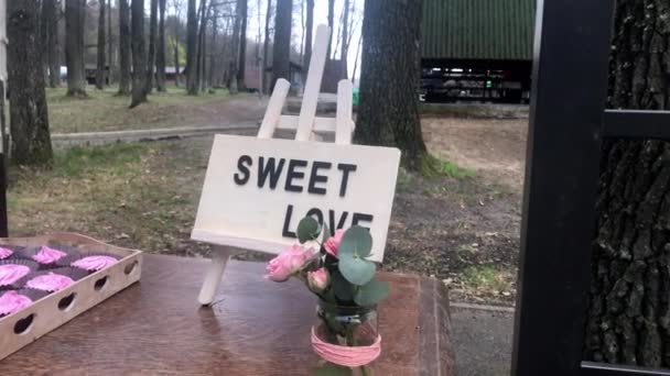 Área decorativa de la boda con bebidas con limonada, cupcakes y un signo con la frase dulce amor — Vídeo de stock