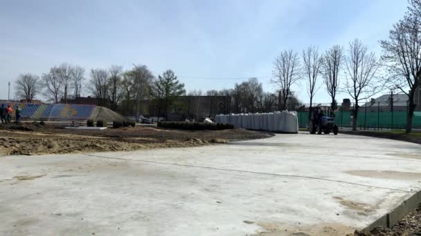 LVIV, UKRAINE - 14 de abril de 2019: Construção do estádio. Trabalhadores que viajam em um trator em uma pista de concreto . — Vídeo de Stock