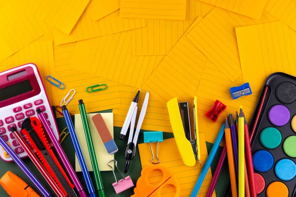 オレンジ色の紙の背景に文房具を提供する学校事務 — ストック写真