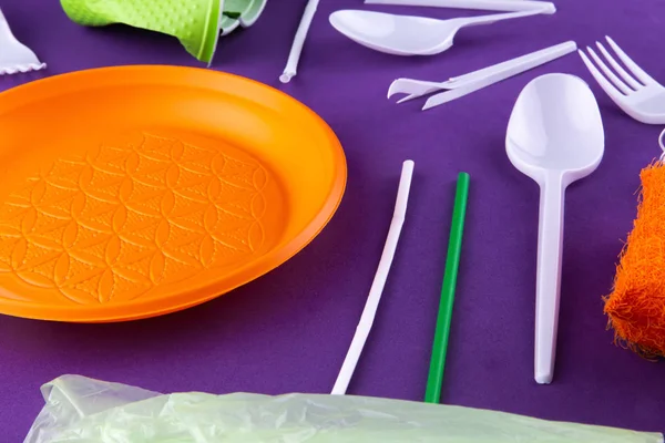 Plastic orange green waste collection on purple background. Conc