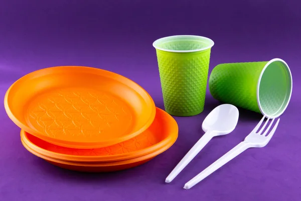 Plastic orange green waste collection on purple background. Conc