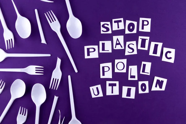 The word stop plastic pollution made of cut paper on a purple ba