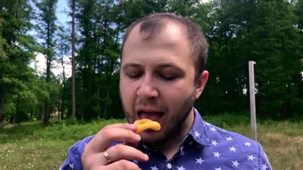 Portrait au ralenti gros plan d'un jeune homme qui mange des chips de tortilla à l'extérieur — Video