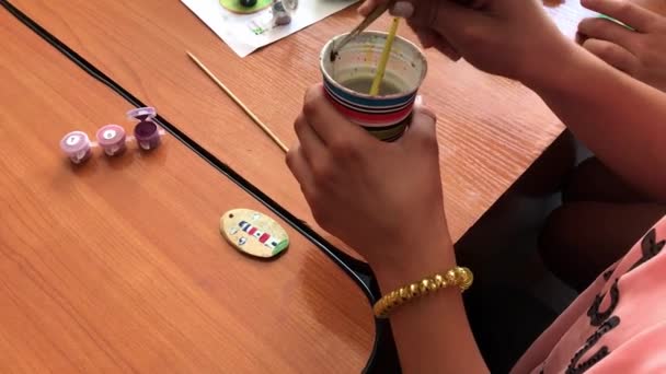 Tiro de close-up de uma criança pintando uma pequena redução de madeira na cor verde. Actividade artesanal — Vídeo de Stock