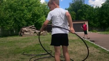 Korosten - Jule, 4, 2019: Güzel sabah bahçesinde erkek çocuk göğüs ve bel dönüş hula çember halka sıyrık yakın çekim.