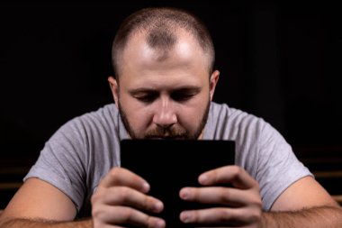 Genç bir adam bir kilise bankında oturur, İncil okur ve dua eder. T