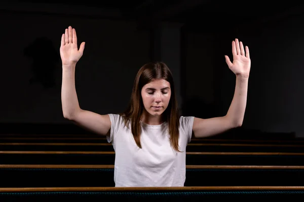 Křesťanská dívka v bílé košili sedí s rukama nad hlavou a — Stock fotografie
